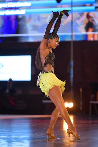 Dancesport competitor: Female dancer: black long-sleeved mesh top with sequin embellishments and a lime