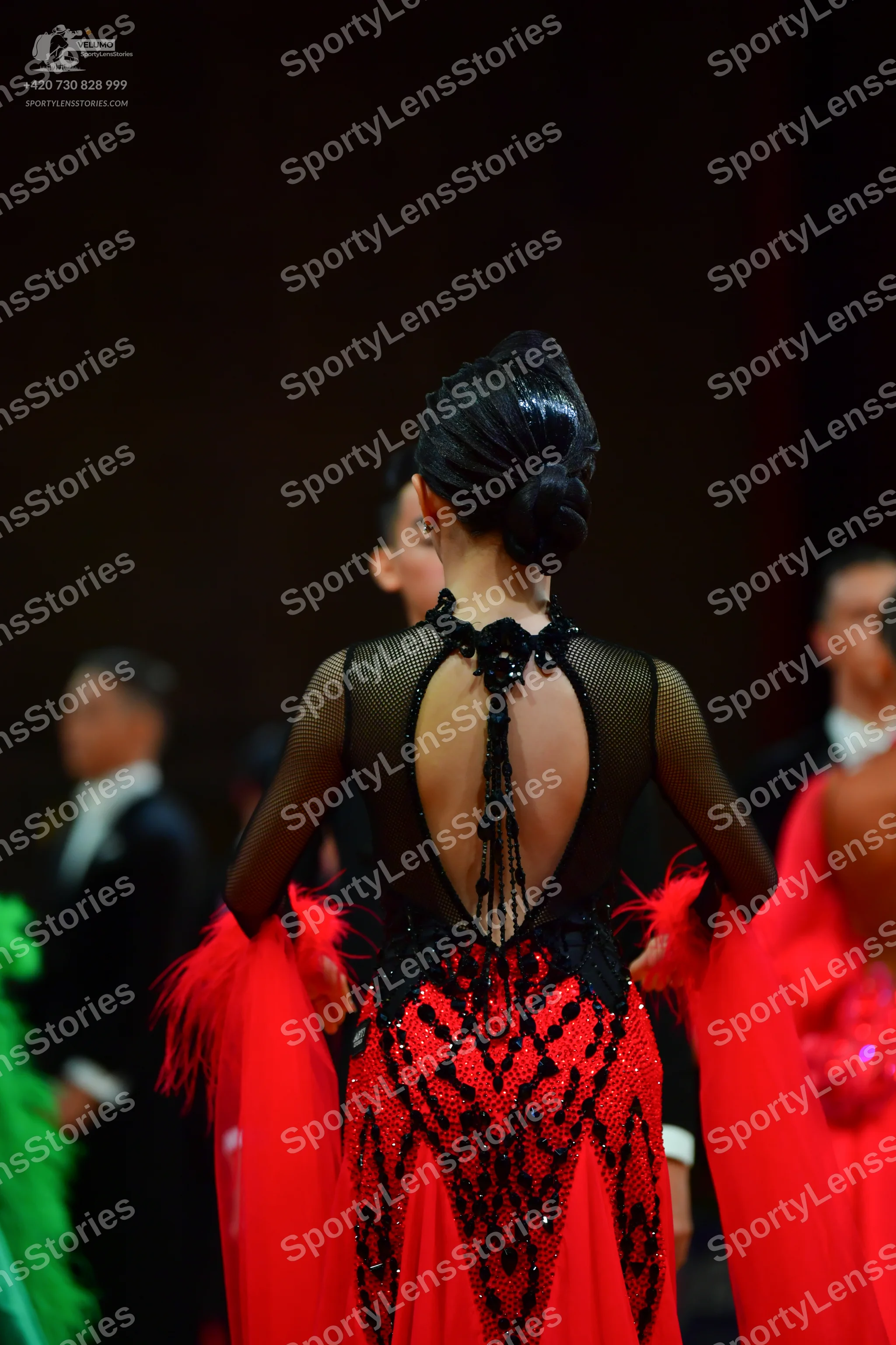 Dancesport competitor: Female dancer: red and black Latin dress with a black sheer mesh upper part, bla