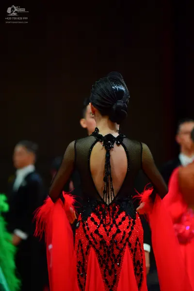 Dancesport competitor: Female dancer: red and black Latin dress with a black sheer mesh upper part, bla