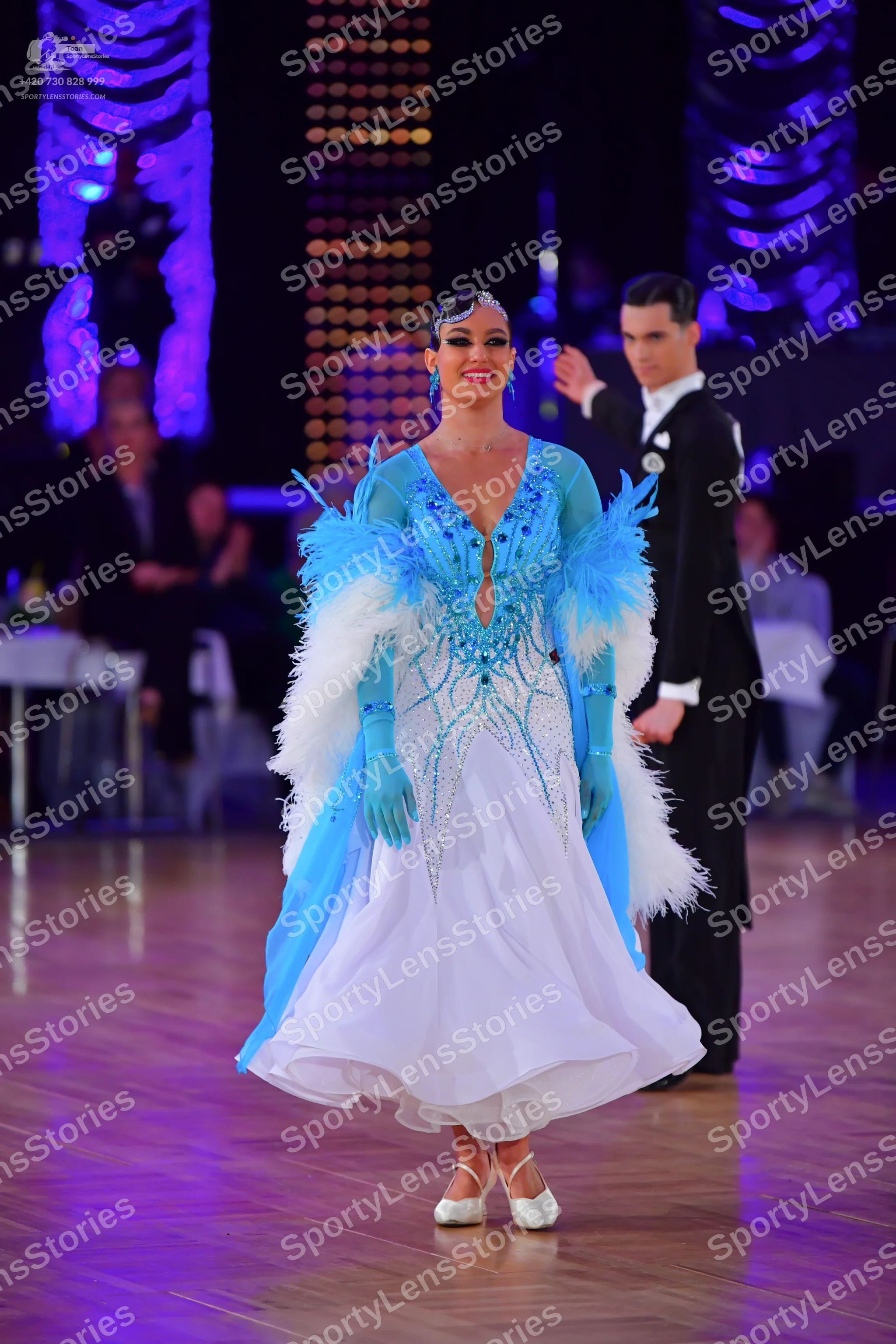 Dancesport competitor: Female dancer: light blue and white ballgown with crystal embellishments, deep V