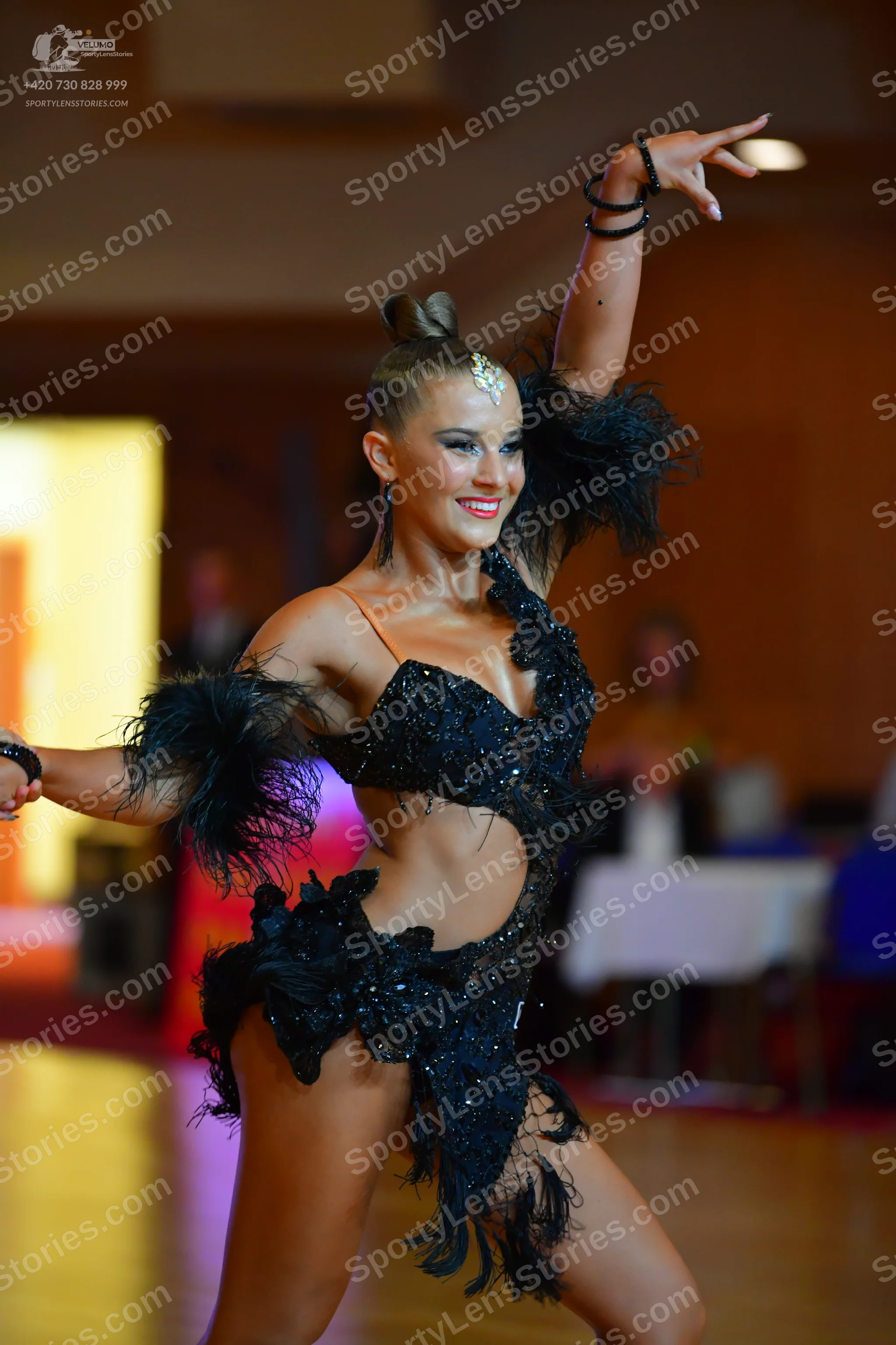 Dancesport competitor: Female dancer: black latin dance costume with sequins and black feathers, featur