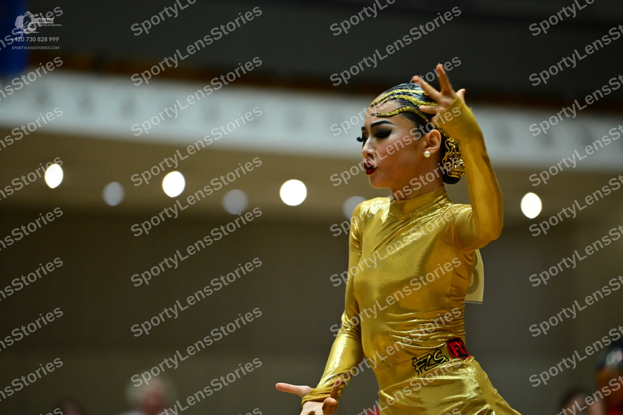 Dancesport competitor: Female dancer: gold metallic long-sleeved Latin dress with a high neckline and a