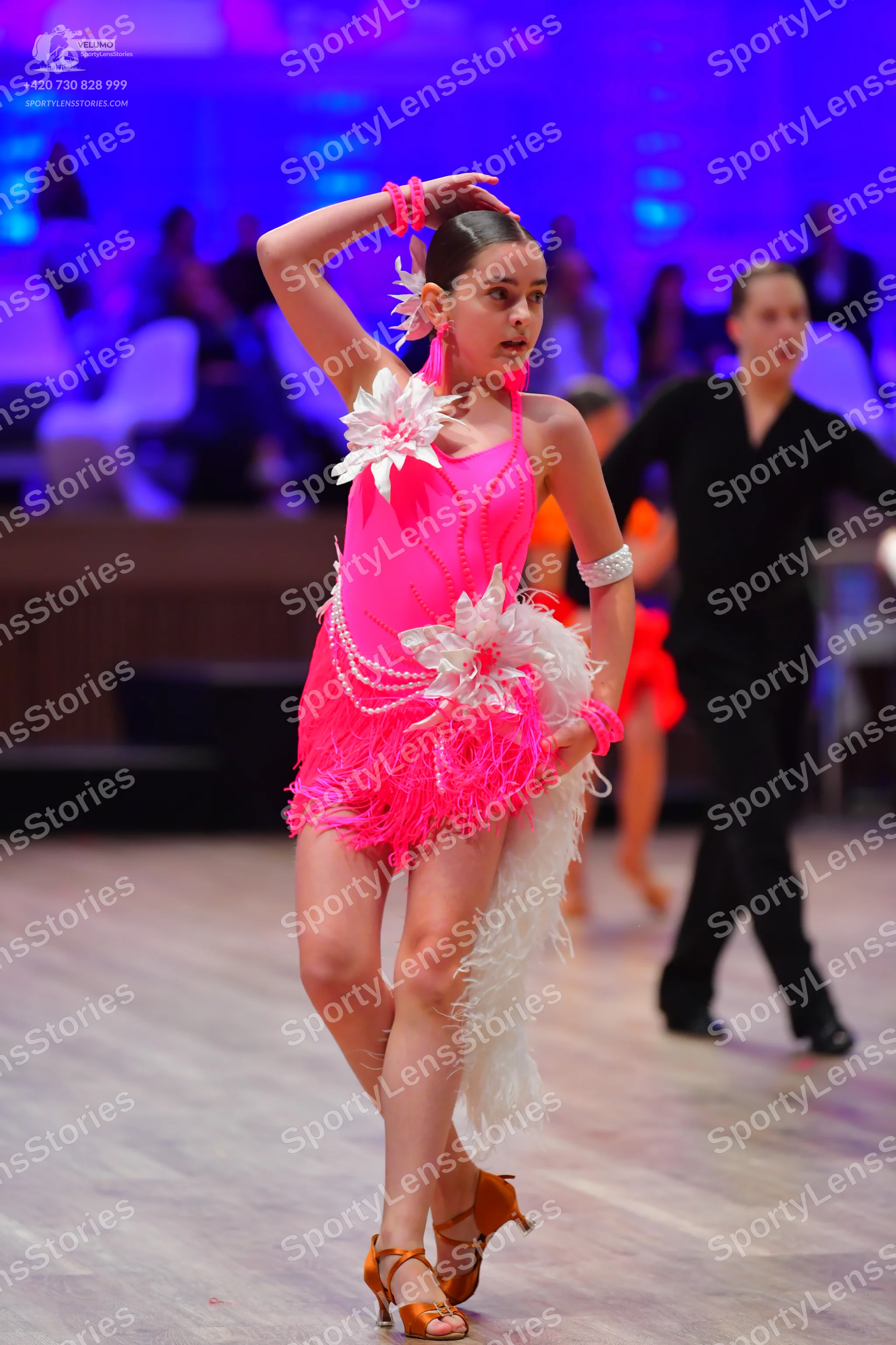 Dancesport competitor: Female dancer: bright pink Latin dress with long fringe and white feather-like e