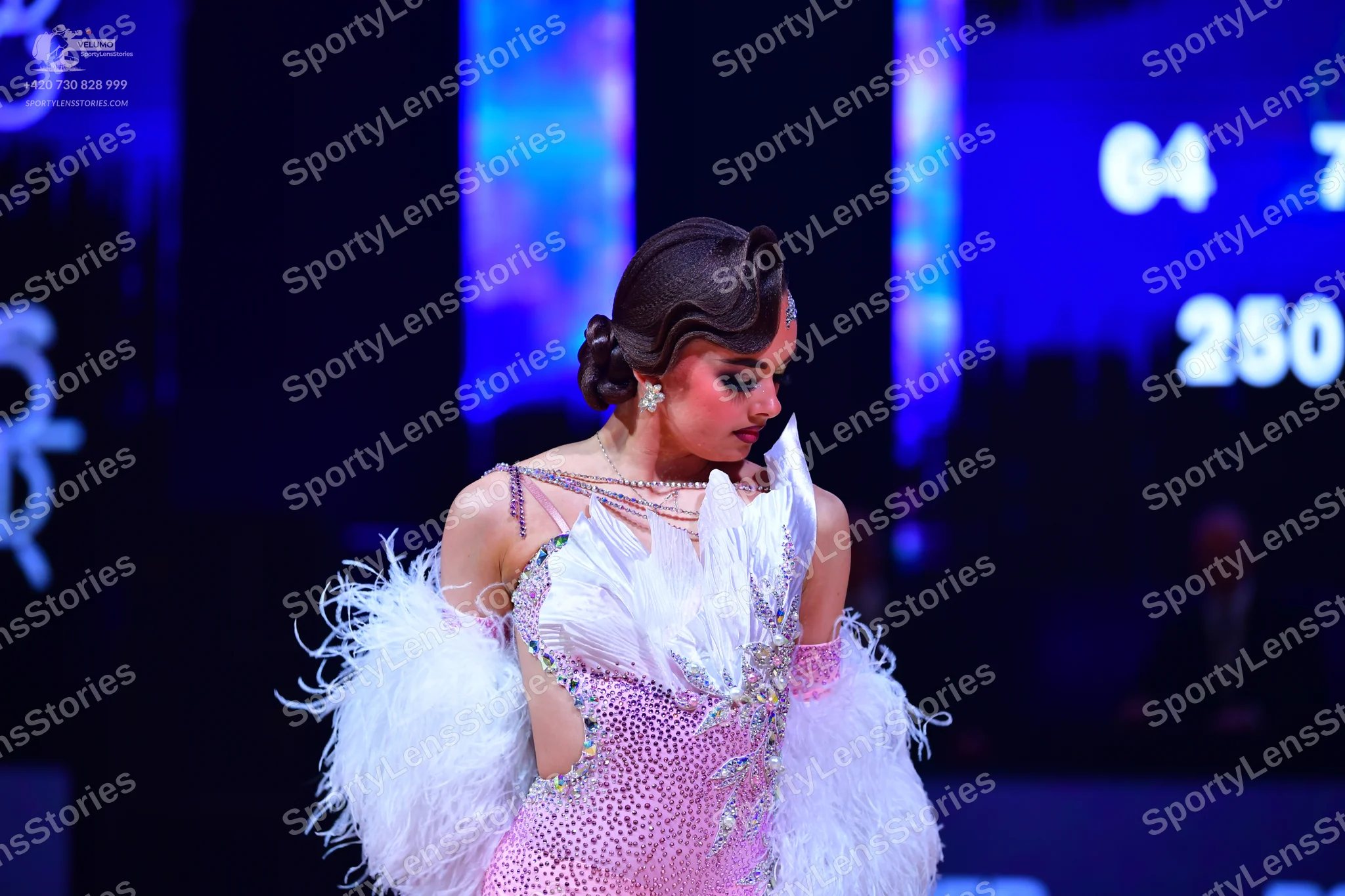 Dancesport competitor: Female dancer: pink sequined Latin dress with large white feather embellishments