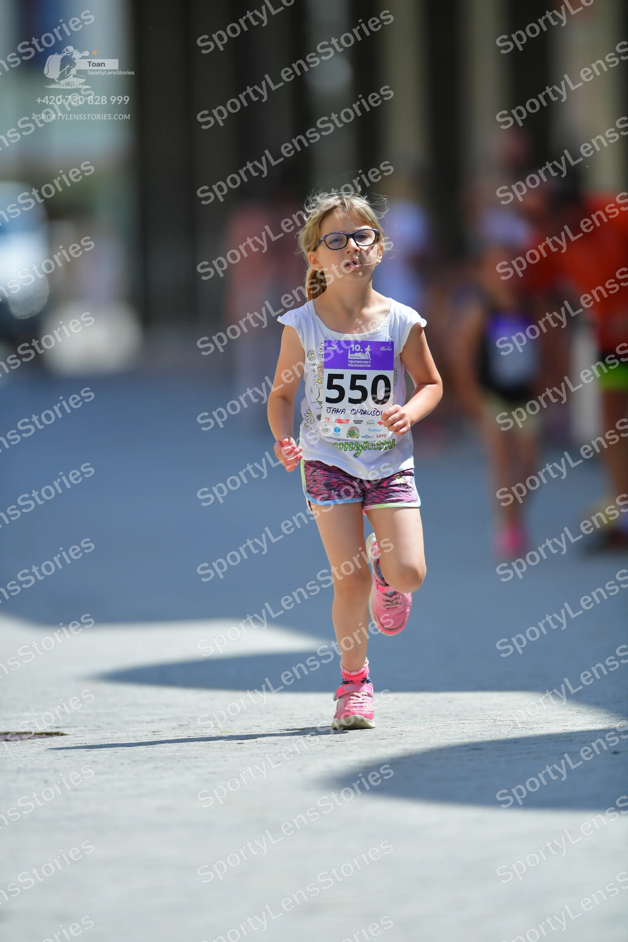 Marathon runner #550: Runner 1: white sleeveless top, purple patterned shorts, pink shoes, glasses