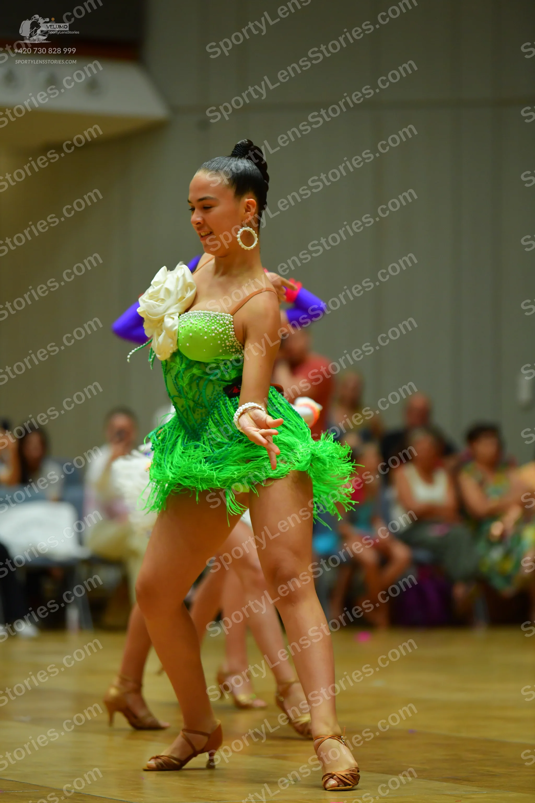 Dancesport competitor: Female dancer: bright green Latin dress with a shimmering/sequined bodice, a lar