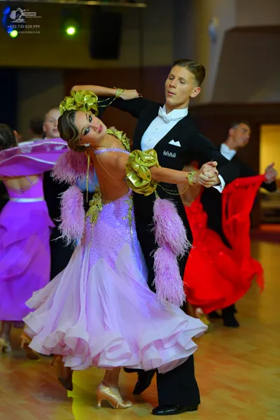 Dancesport competitor: Primary female dancer: lavender ballroom dress with a voluminous ruffled skirt, 
