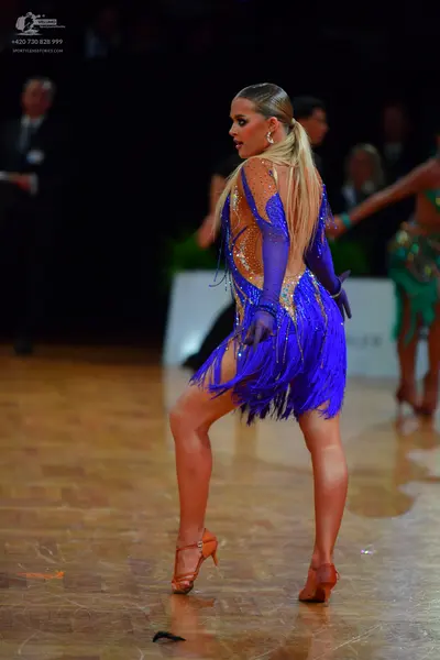 Dancesport competitor: Female dancer in foreground: blue and orange latin dress with fringe and orange/
