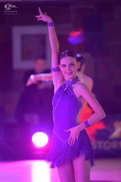 Dancesport competitor: Female dancer: purple latin dress with a sequined bodice, fringe skirt, and matc
