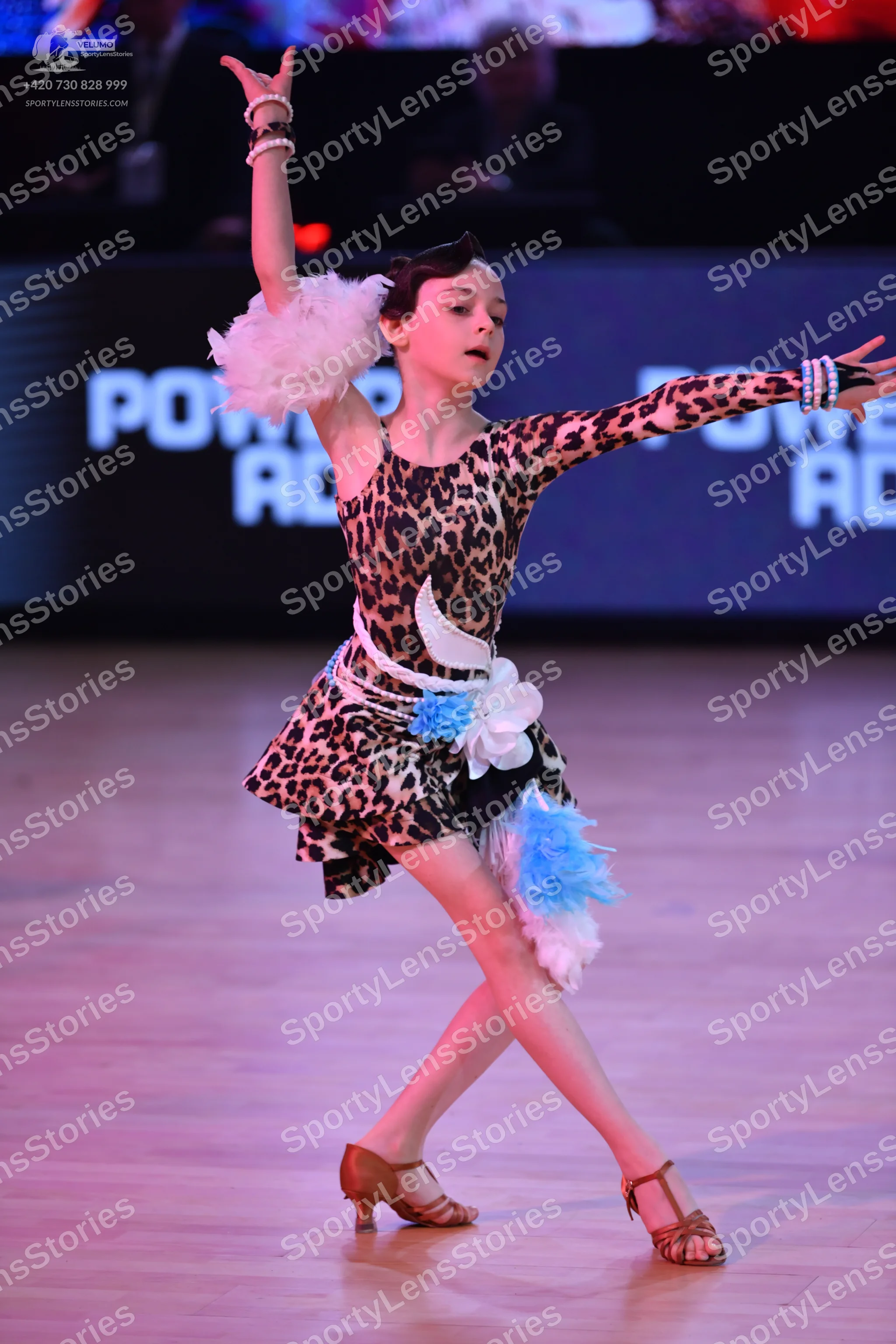 Dancesport competitor: Female dancer: leopard print Latin dress with one sleeve, featuring white and li