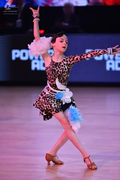 Dancesport competitor: Female dancer: leopard print Latin dress with one sleeve, featuring white and li