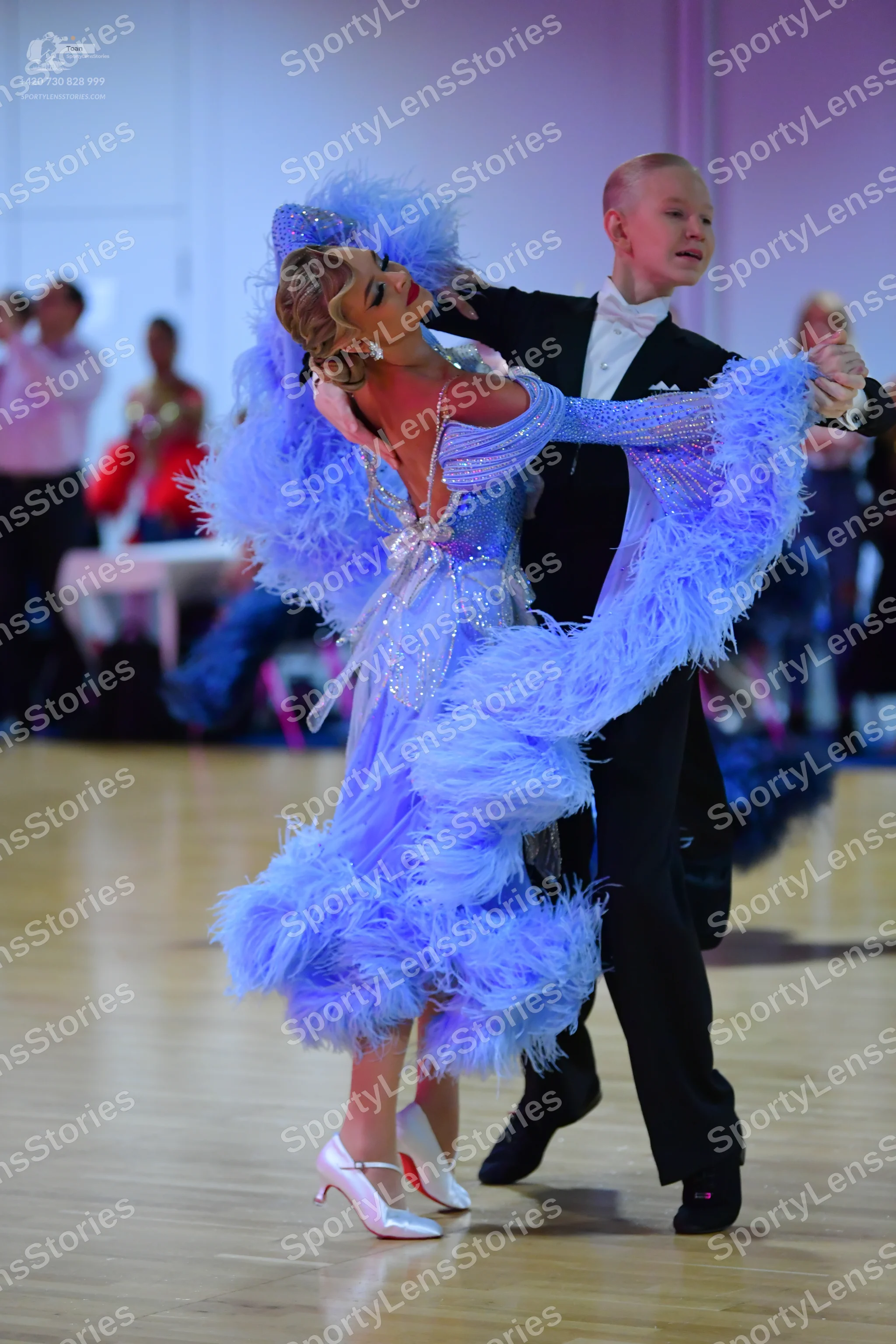 Dancesport competitor: Female dancer: light blue latin dress with sequins and large feather trim on the