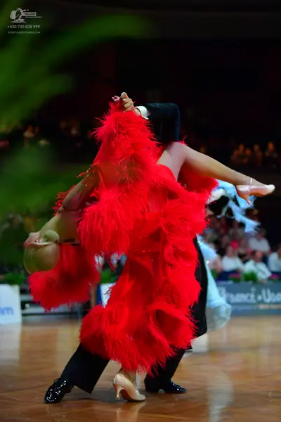 Dancesport competitor: Female dancer: bright red Latin dance dress with long, voluminous fringe