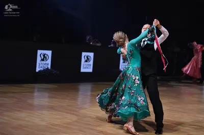 Dancesport competitor: Female dancer: emerald green flowing ballgown with a pink floral pattern and she