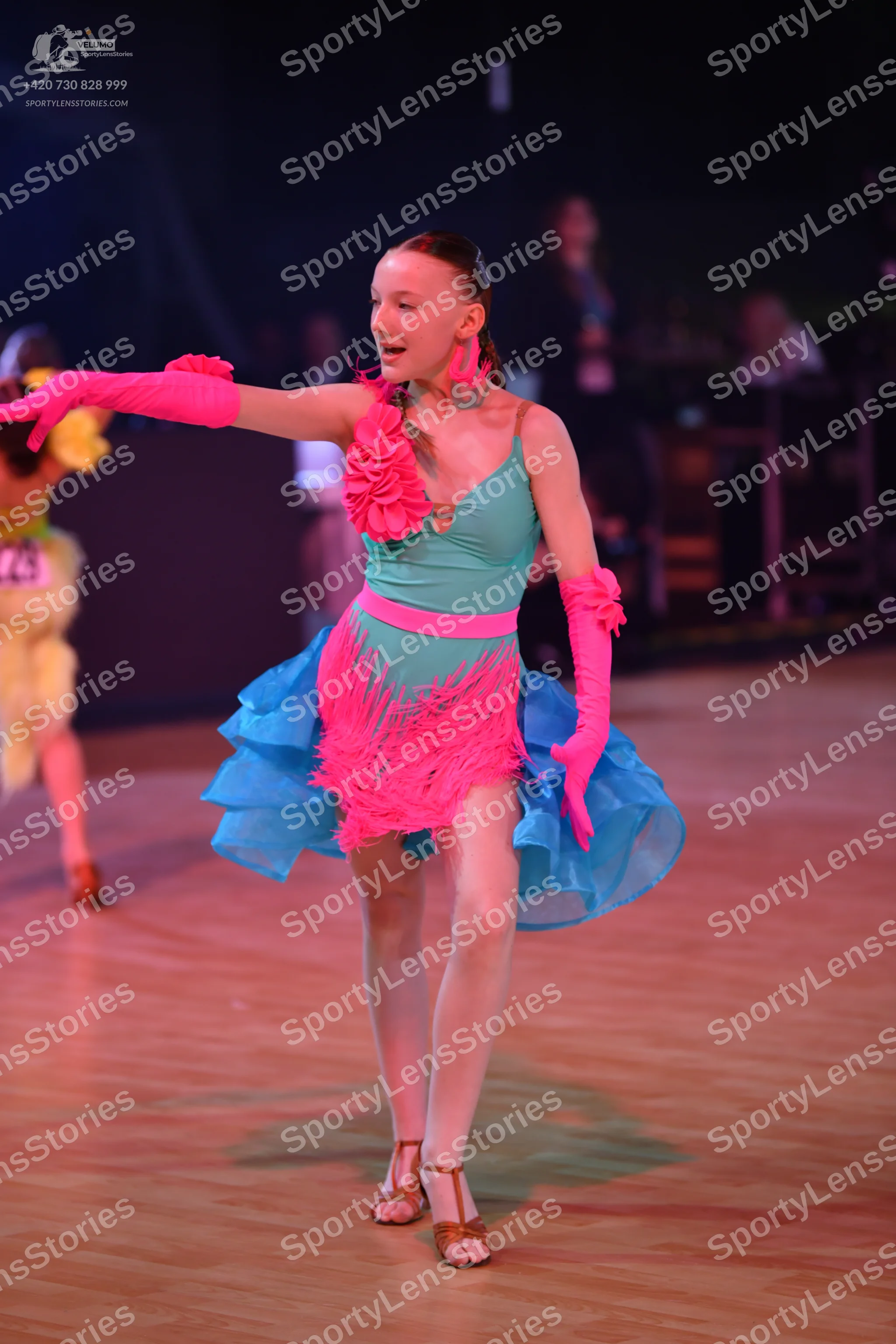 Dancesport competitor: Female dancer in center: turquoise latin dress with pink floral applique, pink f