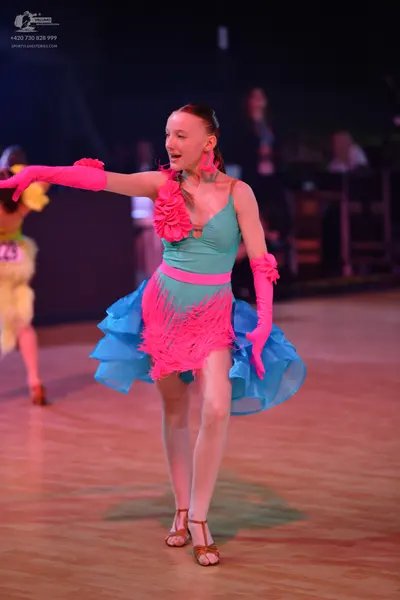 Dancesport competitor: Female dancer in center: turquoise latin dress with pink floral applique, pink f