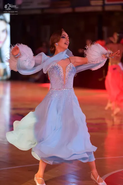 Dancesport competitor: Female dancer: light blue ballgown with a sequined bodice, a flowing skirt, and 