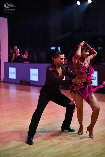 Dancesport competitor: Male dancer: black long-sleeved shirt with pink sequin detailing and black trous
