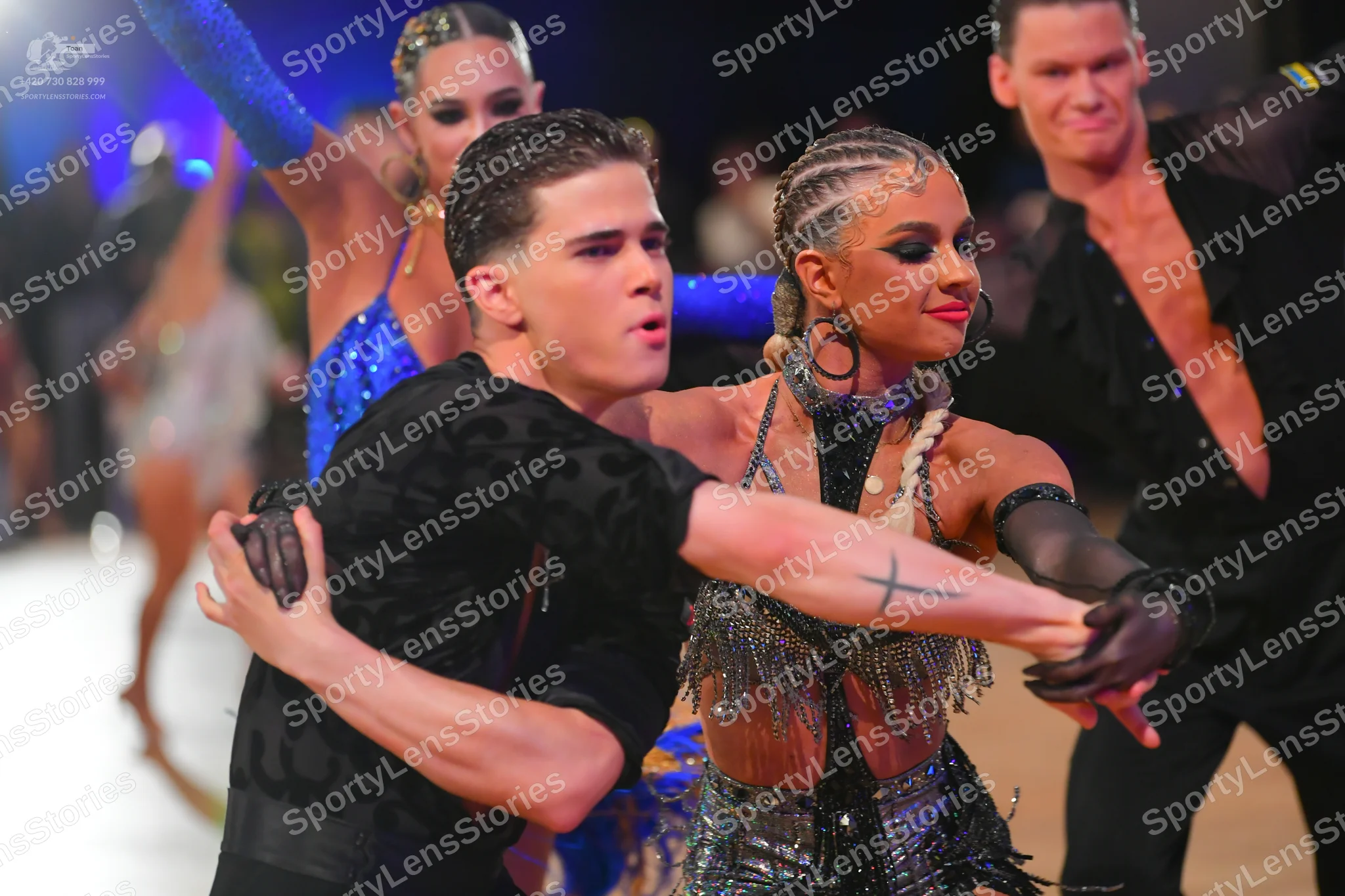 Dancesport competitor: Foreground male dancer: black patterned short-sleeved shirt and black gloves