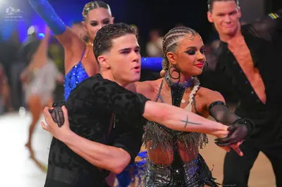 Dancesport competitor: Foreground male dancer: black patterned short-sleeved shirt and black gloves