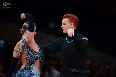 Dancesport competitor: Male dancer: black long-sleeved shirt with a small red detail on the sleeve, a s