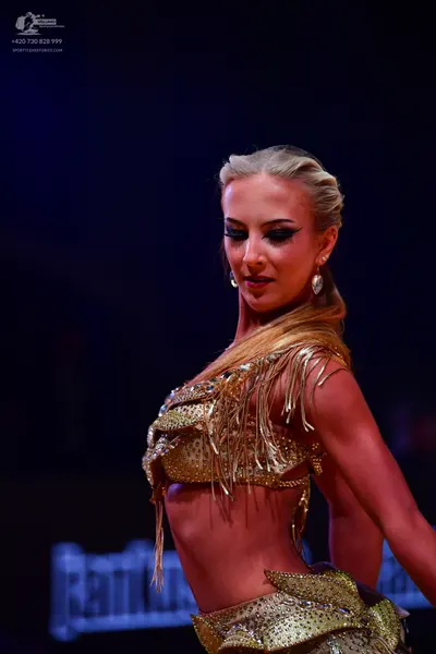 Dancesport competitor: Female dancer: gold two-piece latin costume with heavy sequin and rhinestone emb