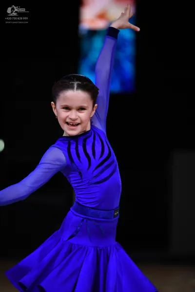 Dancesport competitor: Female dancer: blue latin dress with long sleeves and black wavy patterns on the