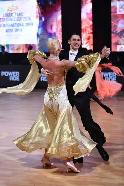 Dancesport competitor: Female dancer: gold and white ballroom gown with a white sequined bodice and a v