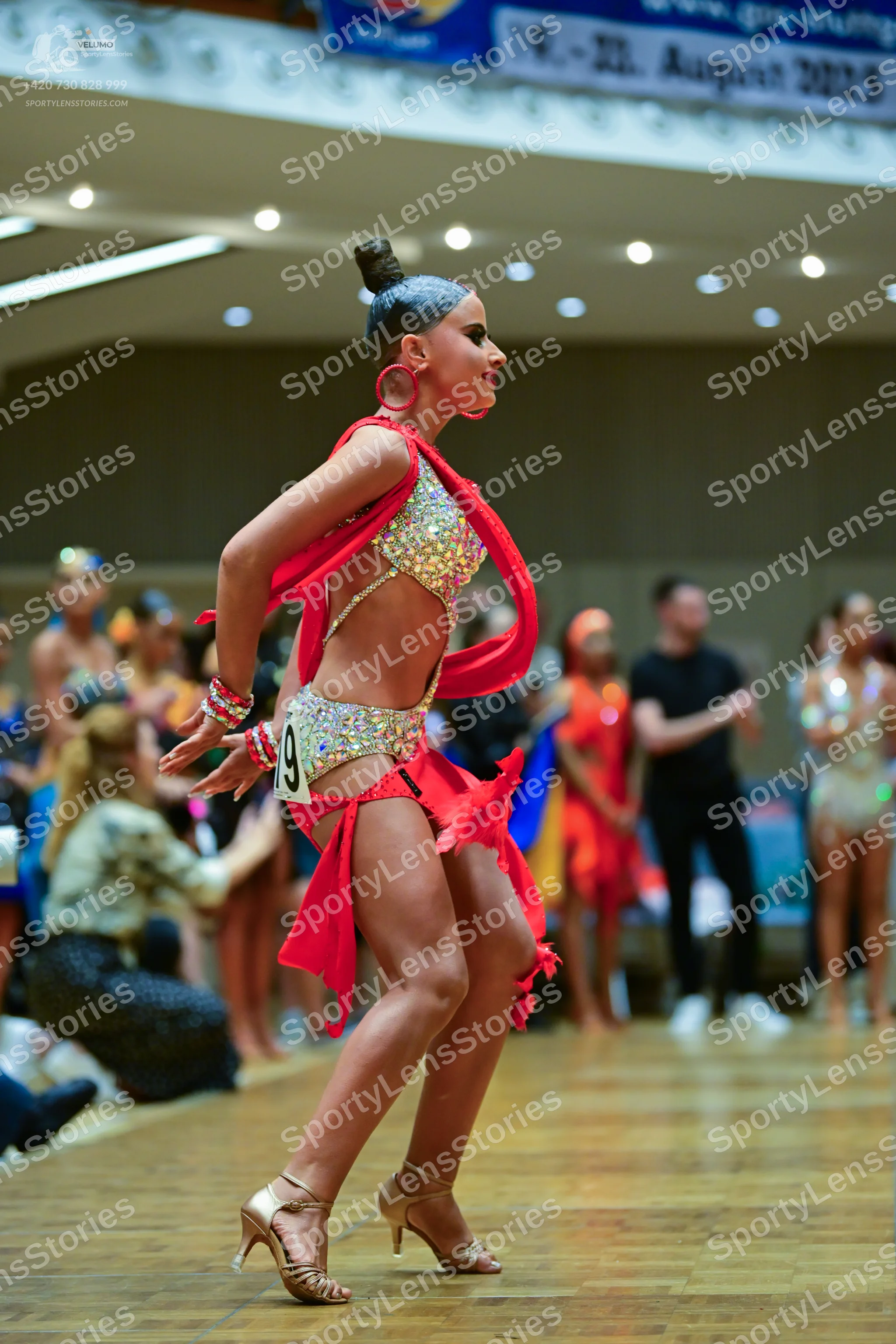 Dancesport competitor: Female dancer in foreground: pink Latin dance costume with a heavily sequined to