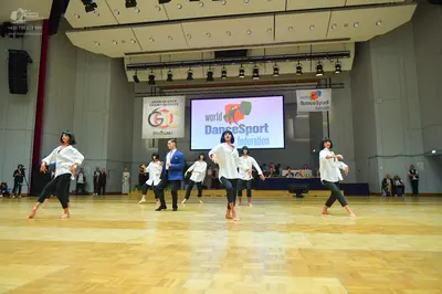 Dancesport competitor: All female dancers are wearing white, loose-fitting long-sleeved blouses and bla