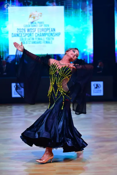 Dancesport competitor: Female dancer: black ballroom dress with gold sequin/beadwork patterns on the bo
