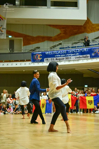 Dancesport competitor: All visible dancers in the foreground are wearing long-sleeved button-up shirts 