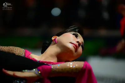 Dancesport competitor: Female dancer: bright pink/magenta Latin dance dress with sheer, nude-toned slee