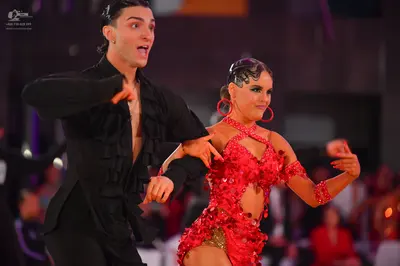 Dancesport competitor: Male dancer: black long-sleeved Latin dance shirt with ruffles on the front and 