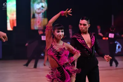 Dancesport competitor: Female dancer: pink/magenta Latin dance costume featuring sequins and fringe, wi