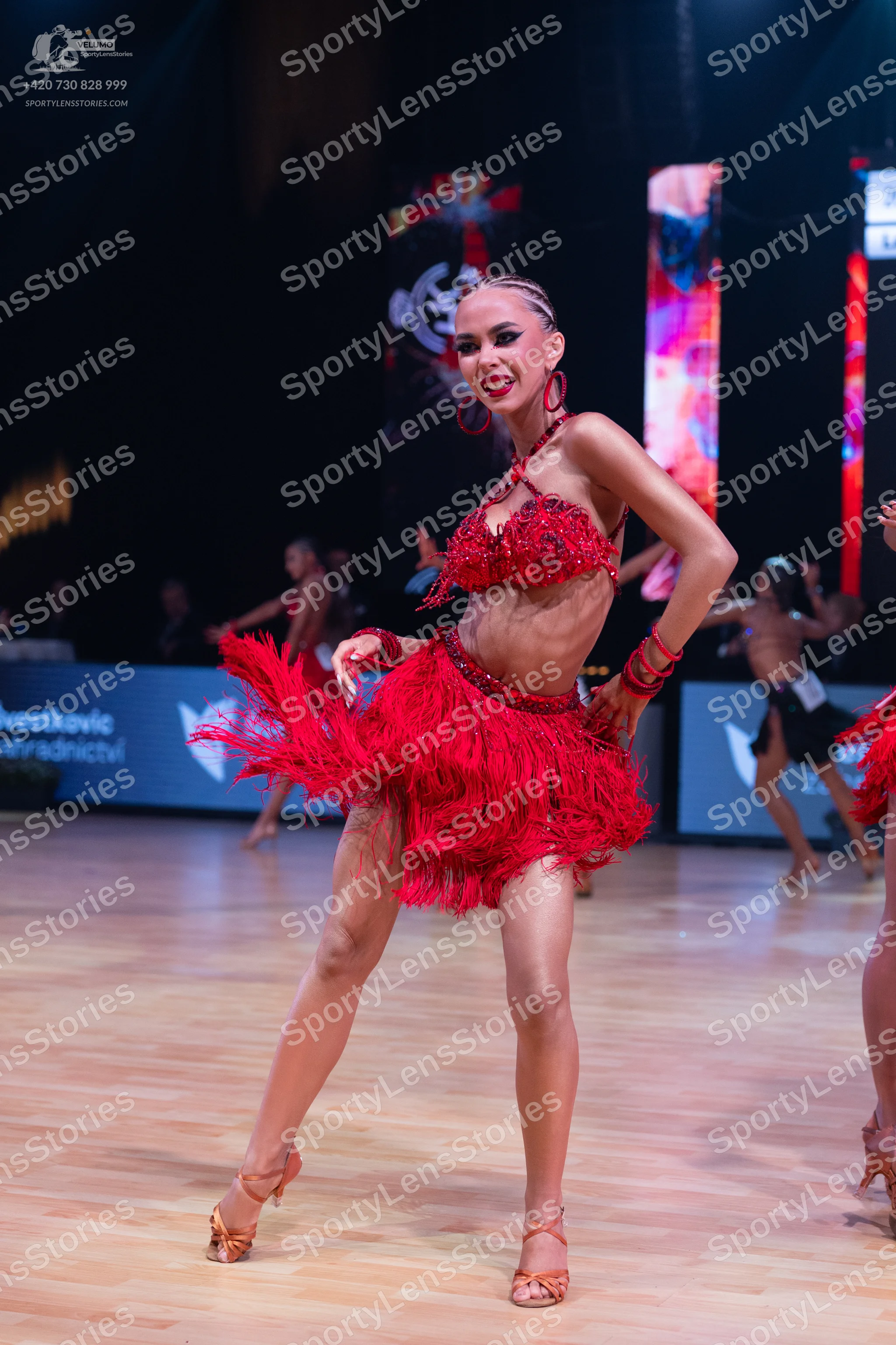 Dancesport competitor: Female dancer: red latin dress with sequin top and fringe skirt, red hoop earrin