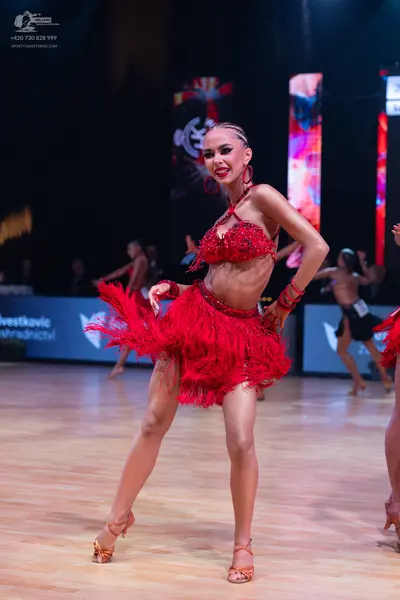 Dancesport competitor: Female dancer: red latin dress with sequin top and fringe skirt, red hoop earrin