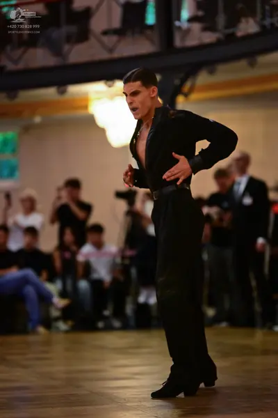 Dancesport competitor: Male dancer: black long-sleeved shirt with a slight sheen, worn open at the ches