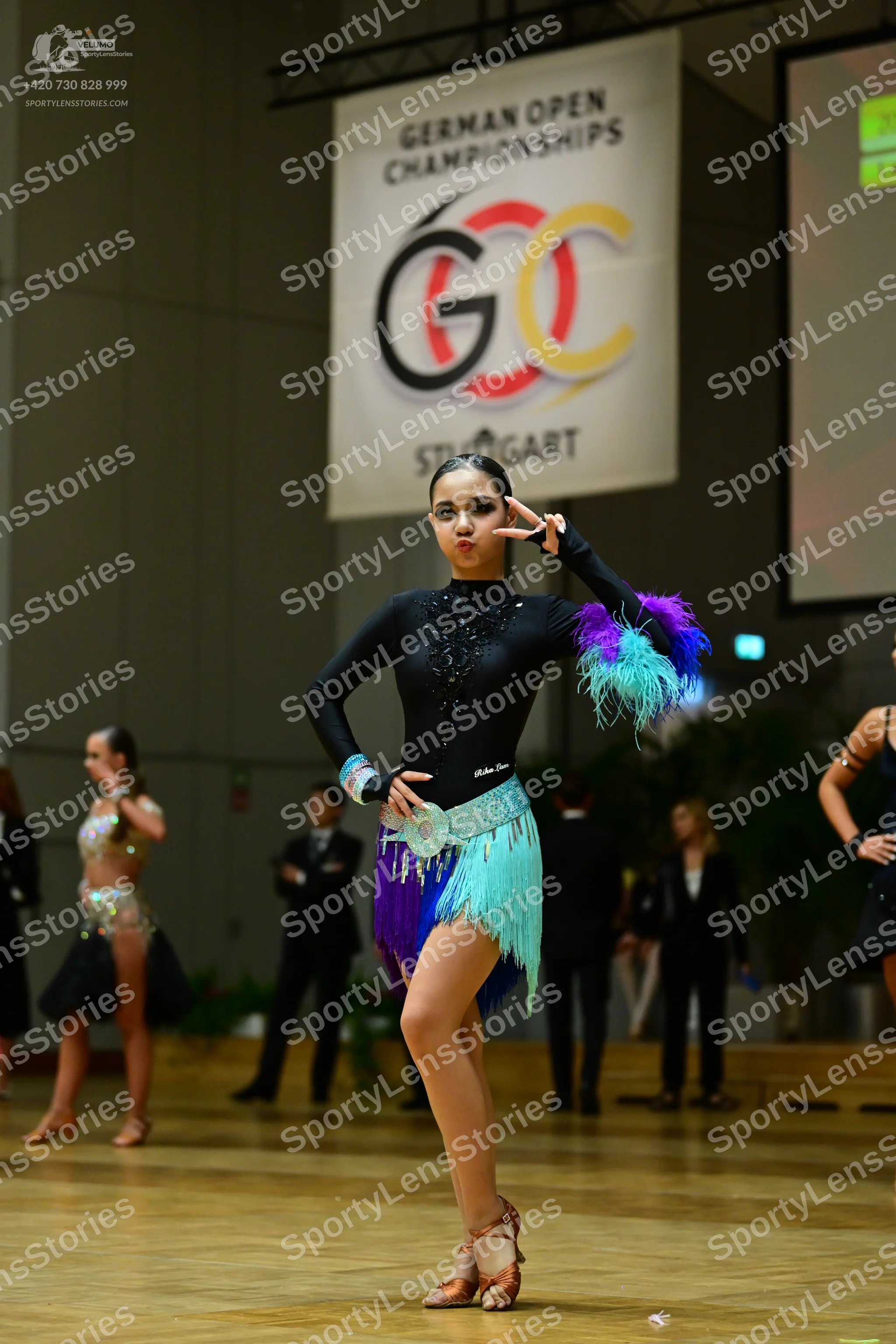 Dancesport competitor: Central female dancer: black long-sleeve latin dress with rhinestone neckline an