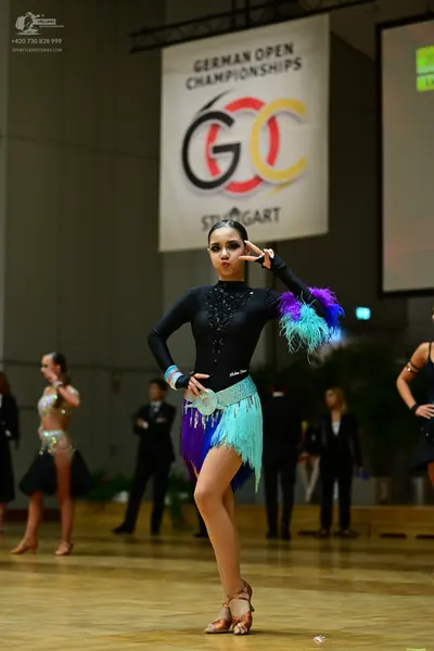 Dancesport competitor: Central female dancer: black long-sleeve latin dress with rhinestone neckline an