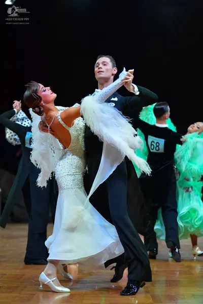 Dancesport competitor #68: Foreground female dancer: white ballgown with a sequined bodice and long white f