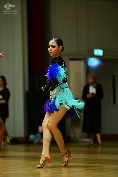 Dancesport competitor: Female dancer: black long-sleeve Latin dance dress with bright blue, purple, and