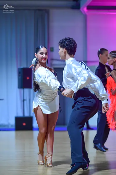 Dancesport competitor: Female dancer: white satin latin dress with long puffed sleeves and an asymmetri
