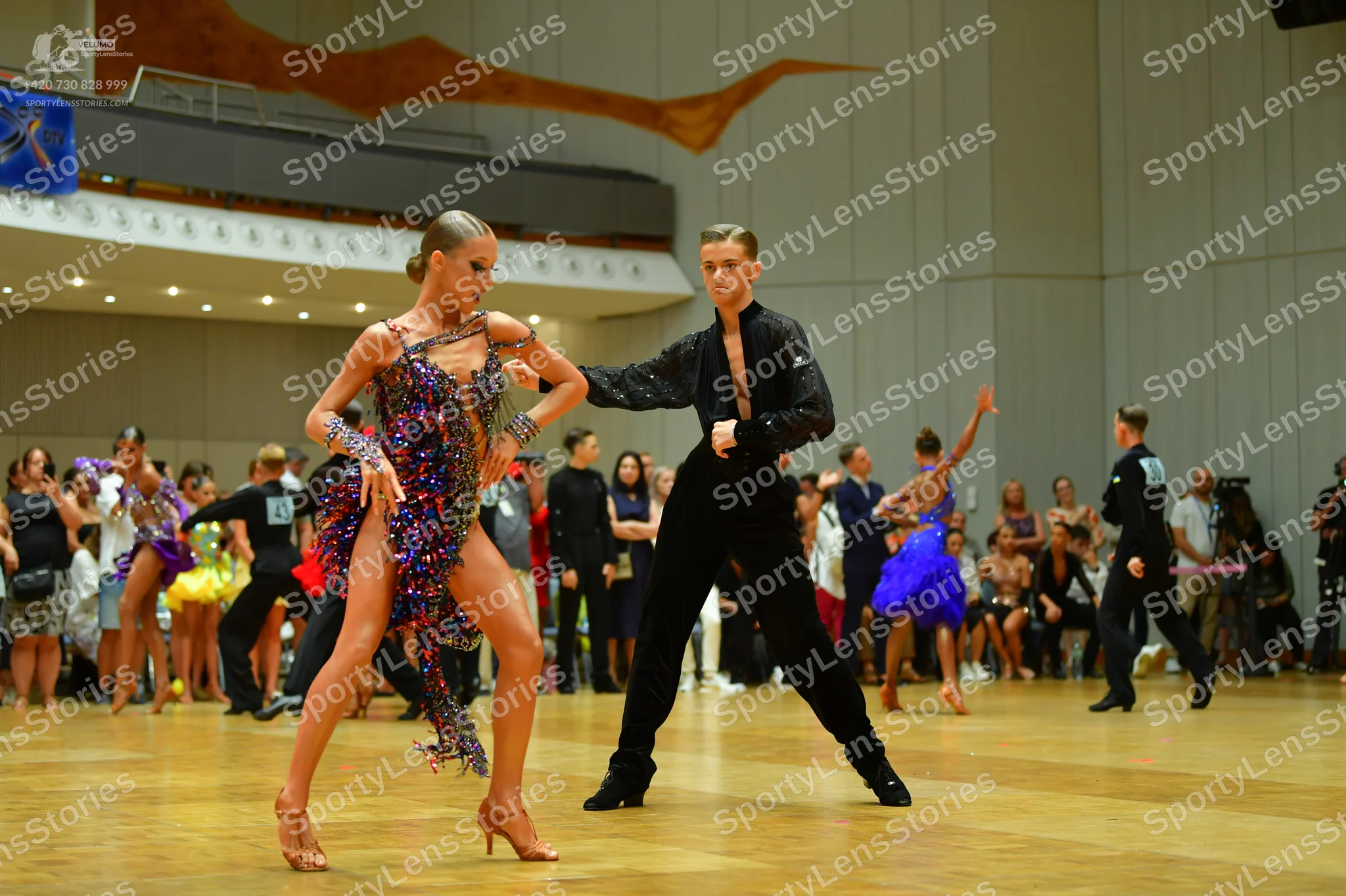 Dancesport competitor: Main female dancer: dark-colored Latin dress with multi-colored sequins in shade