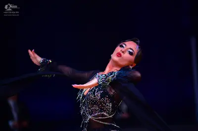 Dancesport competitor: Female dancer: black Latin dress with sheer sleeves, heavily embellished with rh