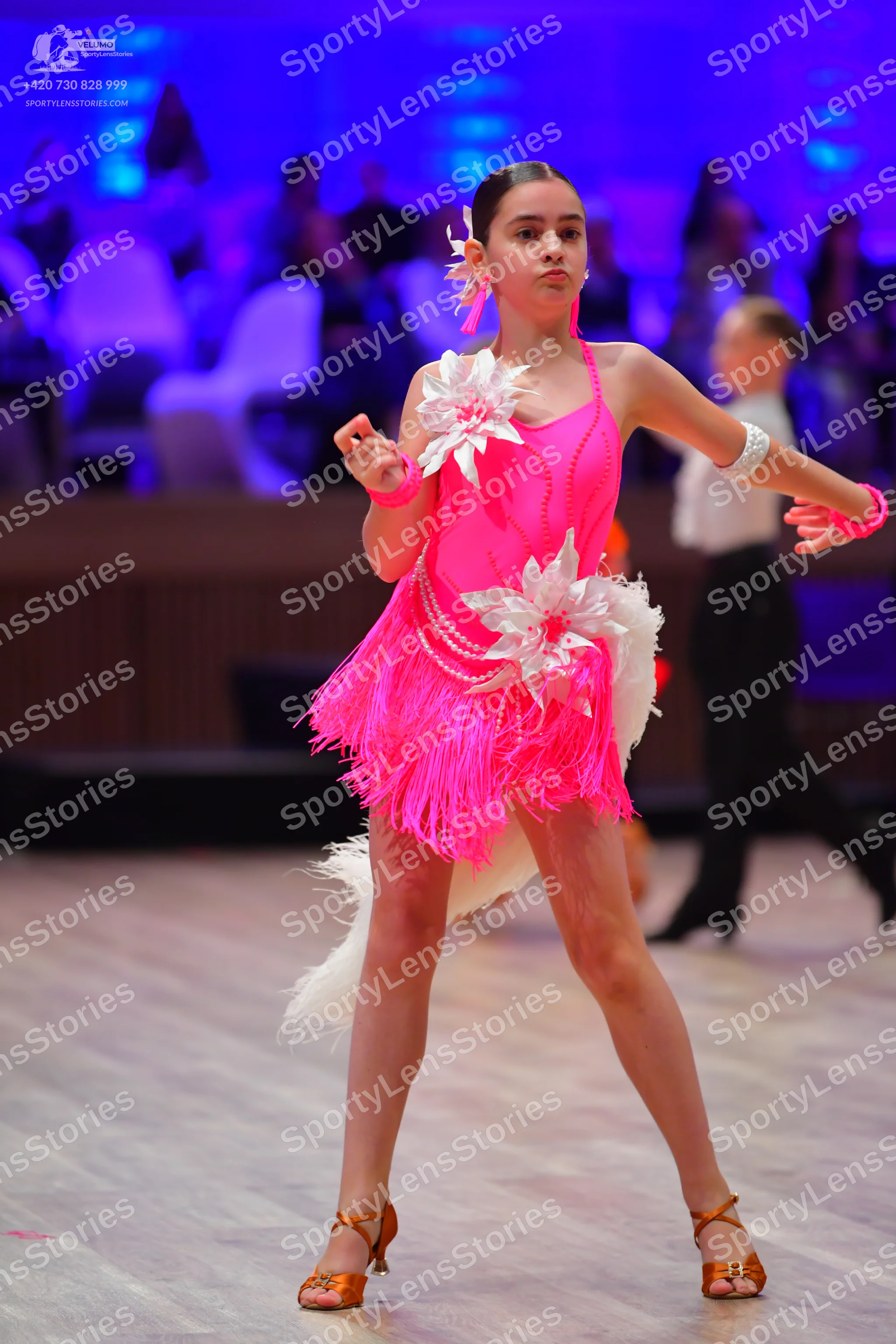 Dancesport competitor: Female dancer: bright pink latin dress with fringe and large white floral embell