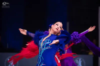 Dancesport competitor: Female dancer in foreground: blue latin dress with silver/light blue sequined sw