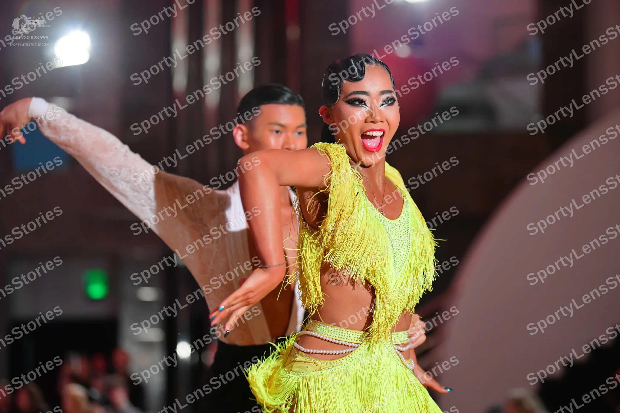 Dancesport competitor: Female dancer: yellow-green Latin dress with fringe and cutouts at the waist