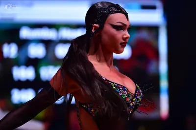 Dancesport competitor: Female dancer: black Latin dance costume heavily embellished with multi-colored,