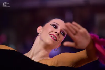 Dancesport competitor: Female dancer: tan-colored Latin dance costume with pink/magenta accents and lar